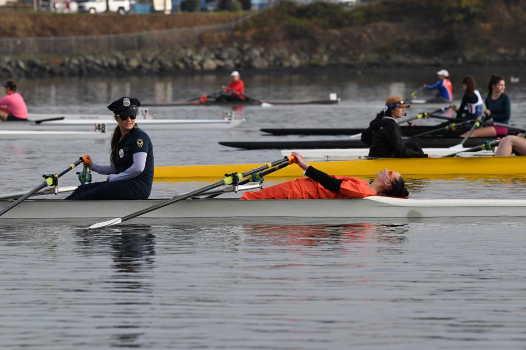 Rowers resting in their boats after the HOG-TOG. In for foreground is a rower dressed as a police officer in the stern, and a rower in an orange jumpsuit in the bow.