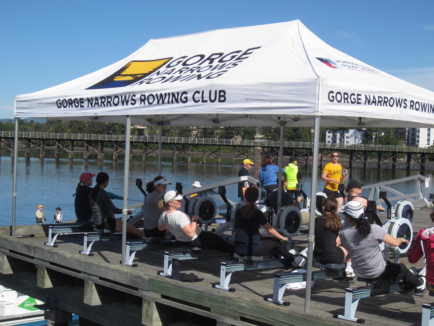 Rowers under the Gorge Rowing tent learning the basics of a stroke with a Concept 2 ERG.