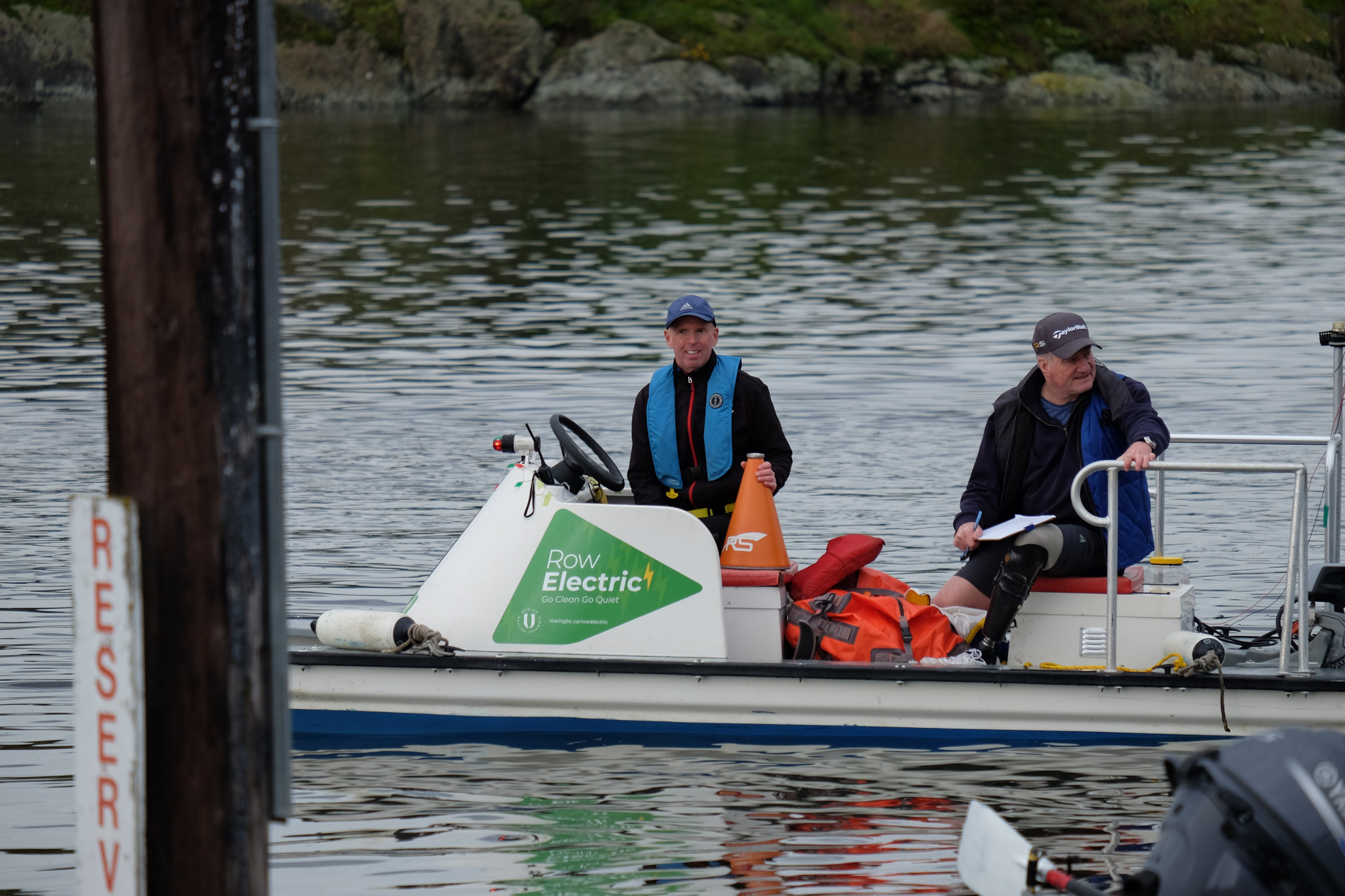 One of the GNRC coach boats, carrying a coach and a volunteer. The boat sports a "Row Electric" logo.