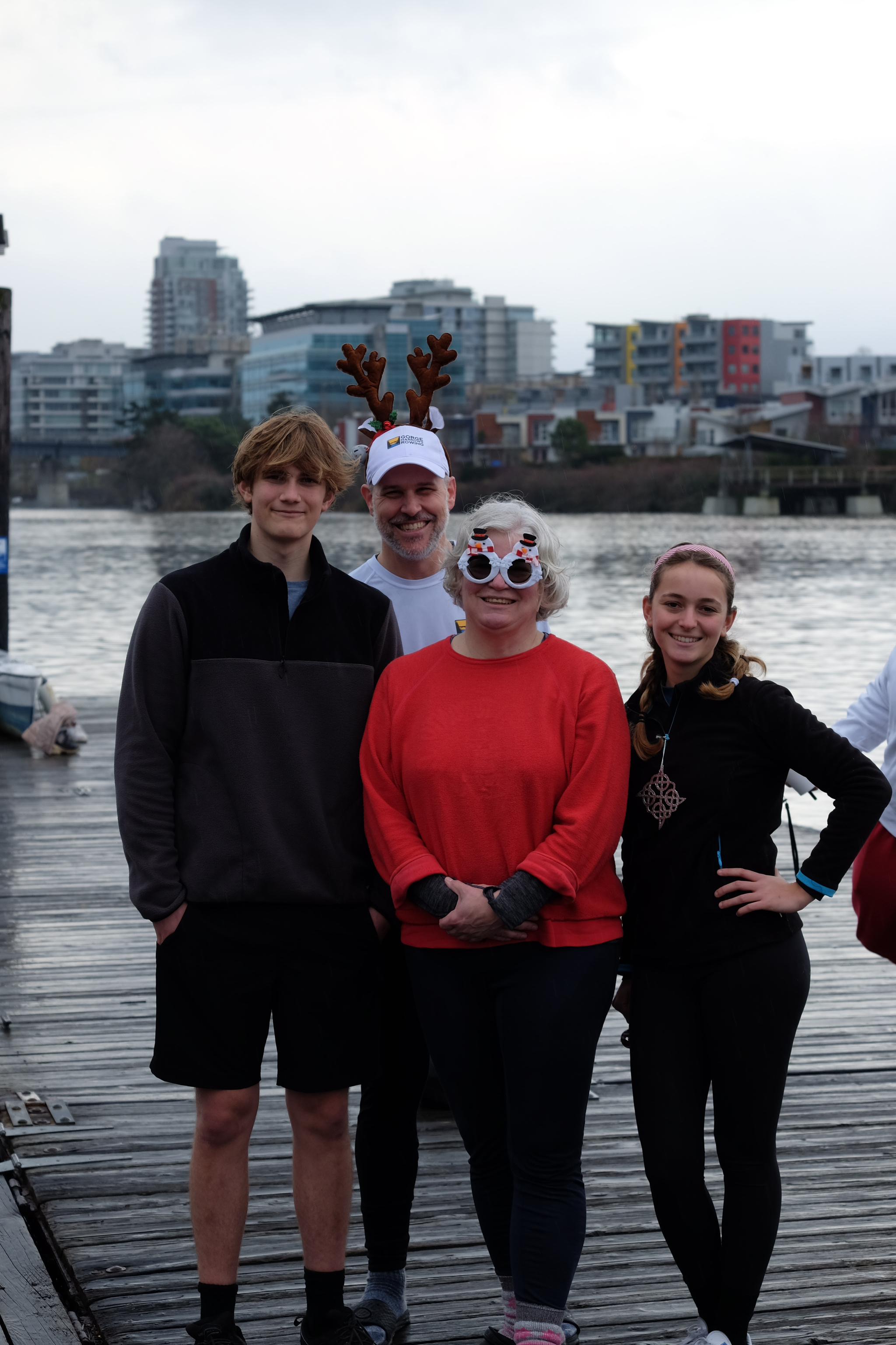 A team of four rowers standing on the dock and posing for a picture.