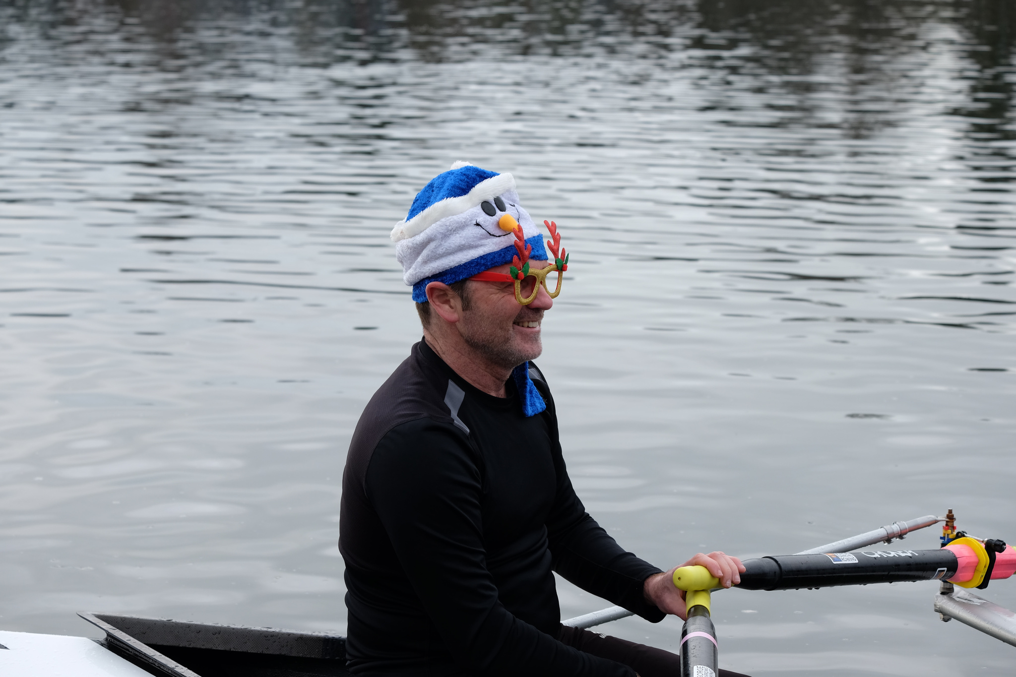 A quad at the dock. Only the athlete rowing the bow position is visible. They are smiling.