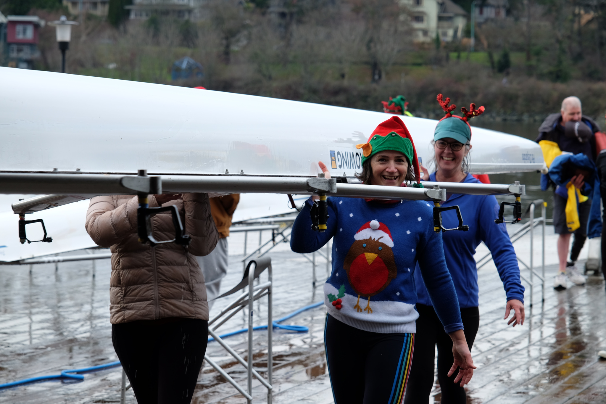 Rowers carrying a cleaned quad into the boathouse.