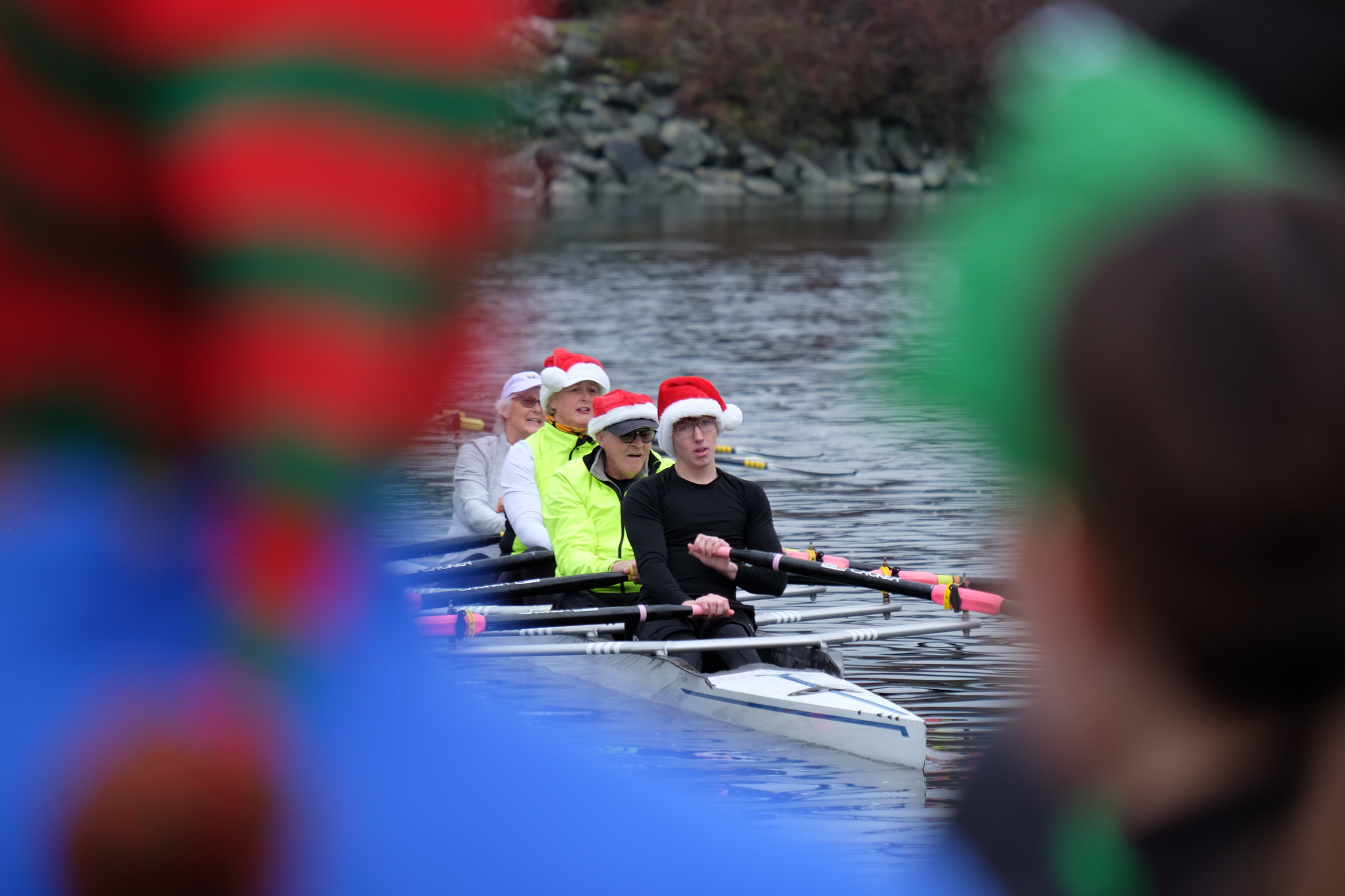 A quad on the water visible between two heads, both sporting holiday hats.