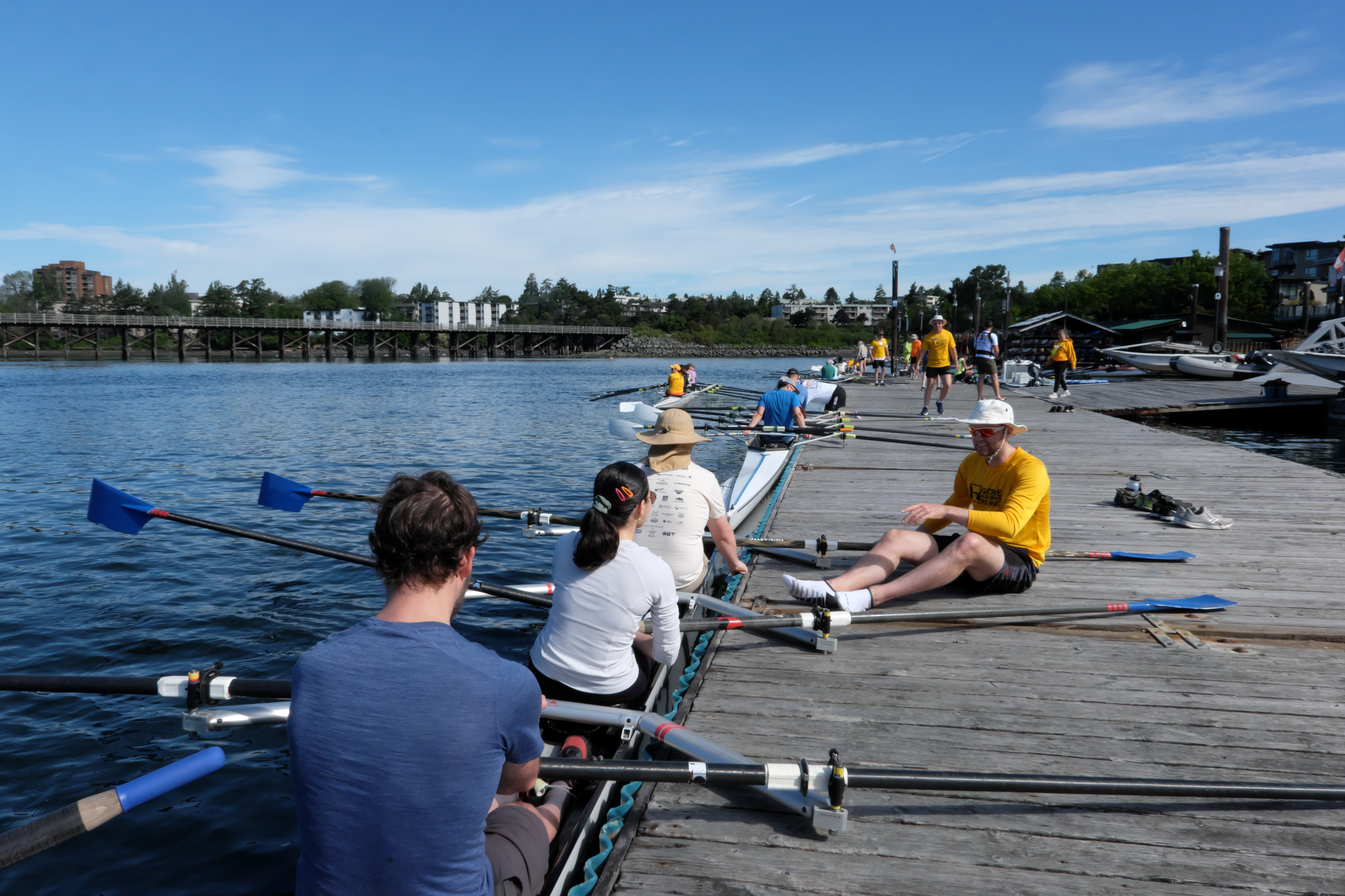 Rowers in a docked boat getting instruction from a coach.