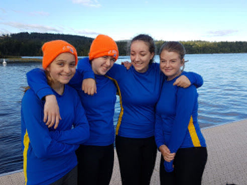Four youth rowers in long sleeved jerseys.