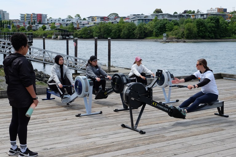New rowers learning the basics of the stroke on a rowing machine.
