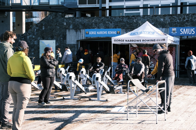 Rowers learning the basics of the stroke on rowing machines on the dock.