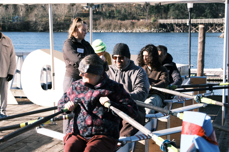 A coach helps participants master the basics of the stroke in a shell on the dock.