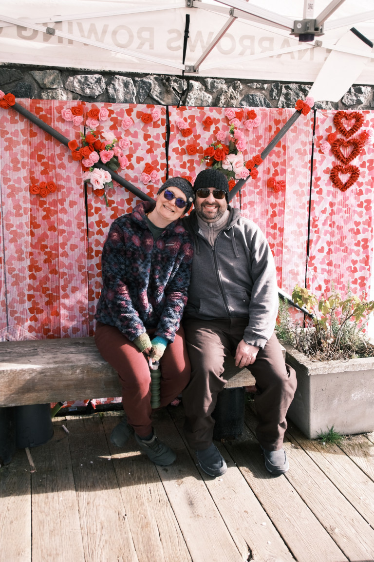 Two Row-Mantic participants against a backdrop of hearts and crossed oars.