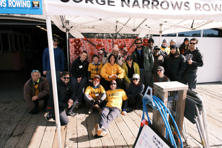 Participants, volunteers, and coaches against a backdrop of hearts and crossed oars!