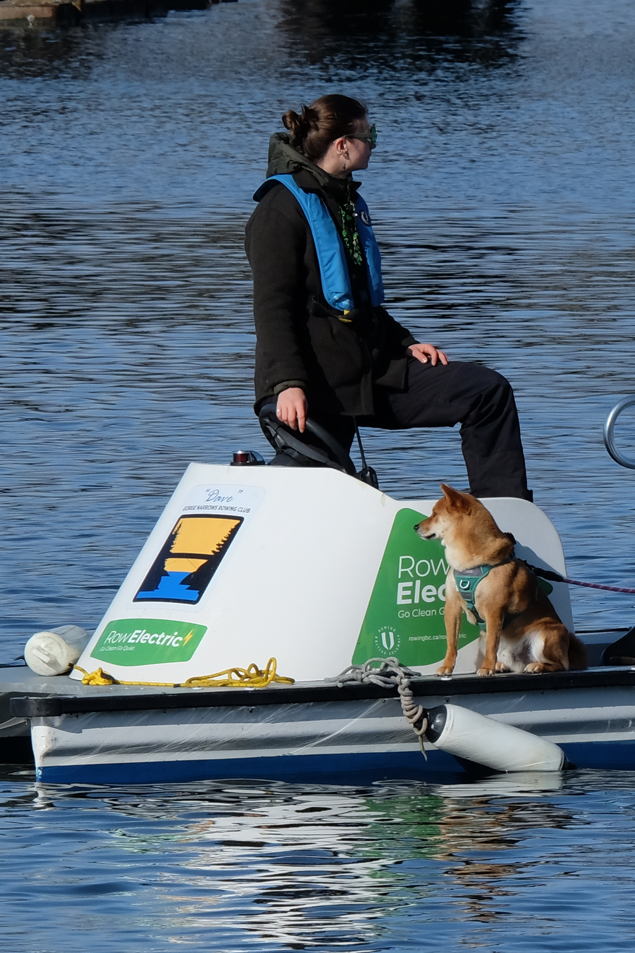 A coach and a dog with a life jacket on one of our electric boats.