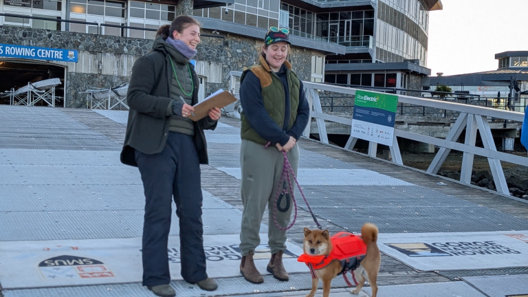 Two coaches, and an extremely cute dog wearing a bright red canine flotation jacket.