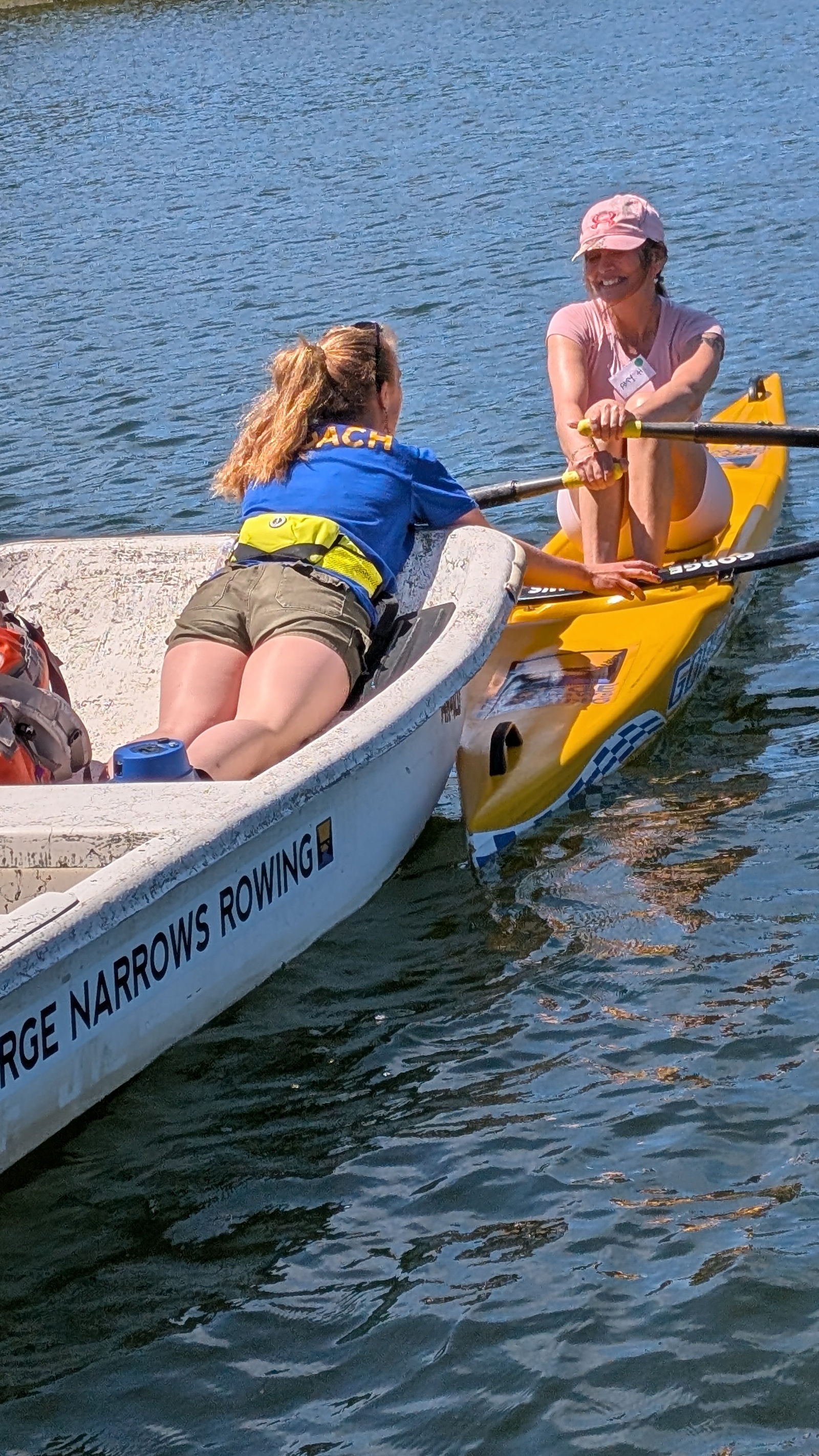A coach helping a new rowers get comfortable in a single.